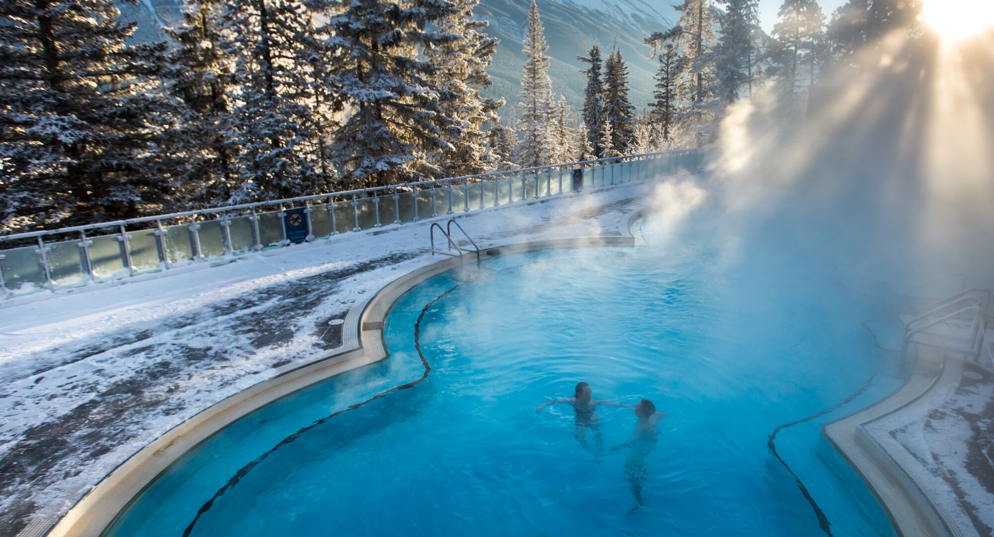 Two people soaking in the Banff Upper Hot Springs on a winters day